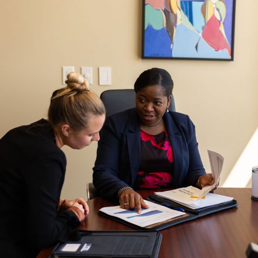 Two female wealth advisors in office reviewing documents
